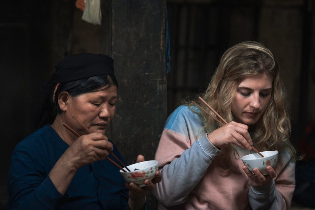 two women using chopsticks for eating